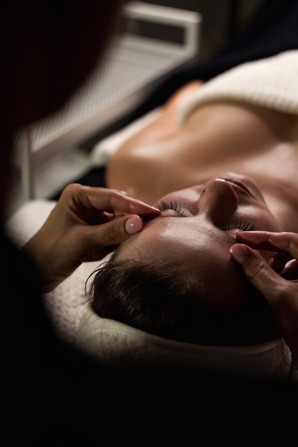 A person enjoys a relaxing facial massage in a serene indoor setting. The massage aims to relieve stress and promote relaxation. Soft lighting enhances the calm atmosphere.